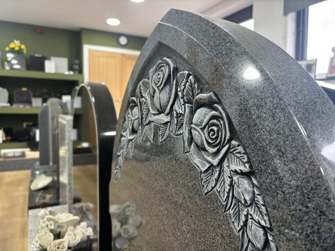 A hand-carved rose detail on a polished granite memorial
